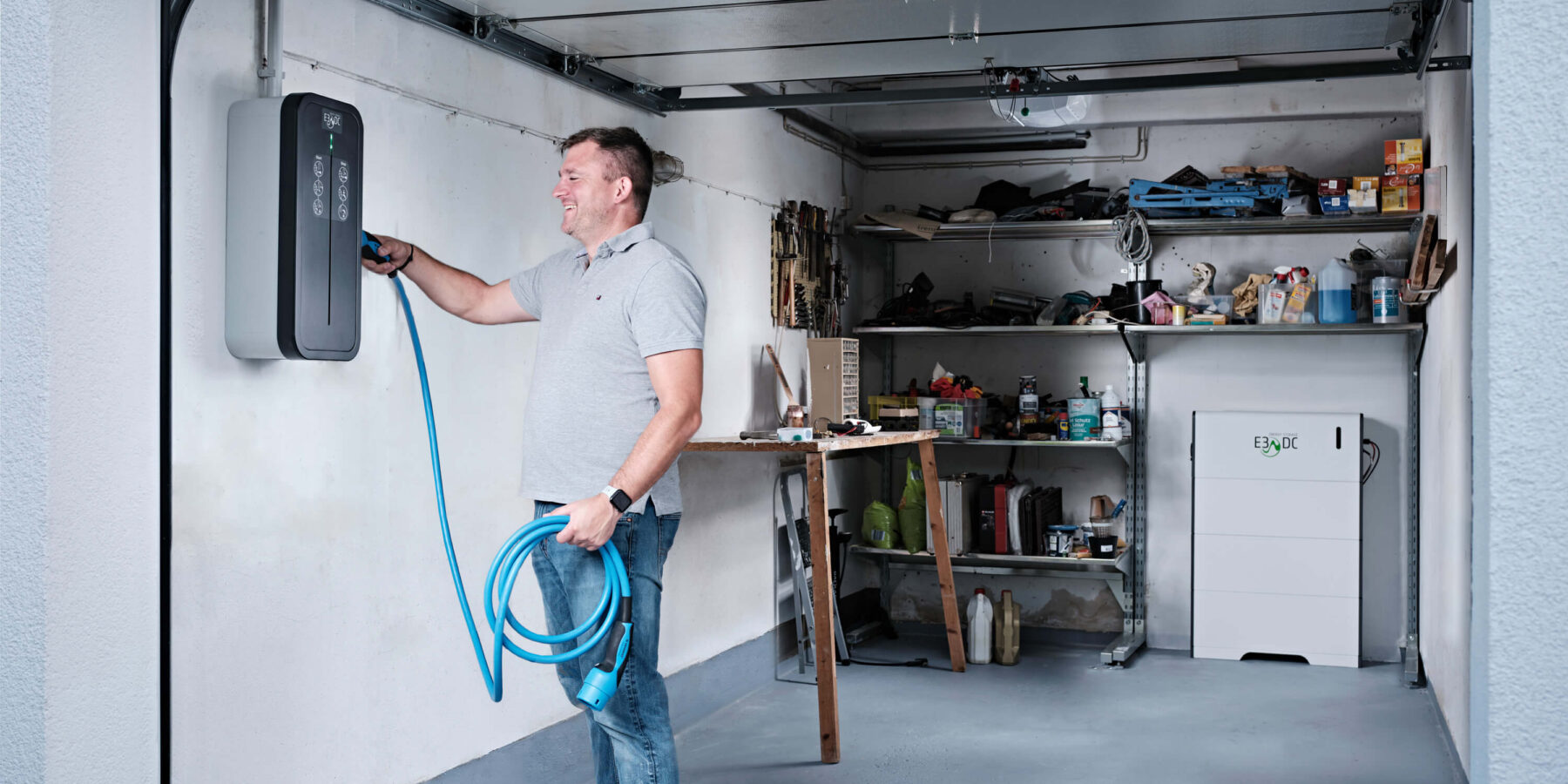 Carsten Paulini steckt das Ladekabel der Wallbox ein