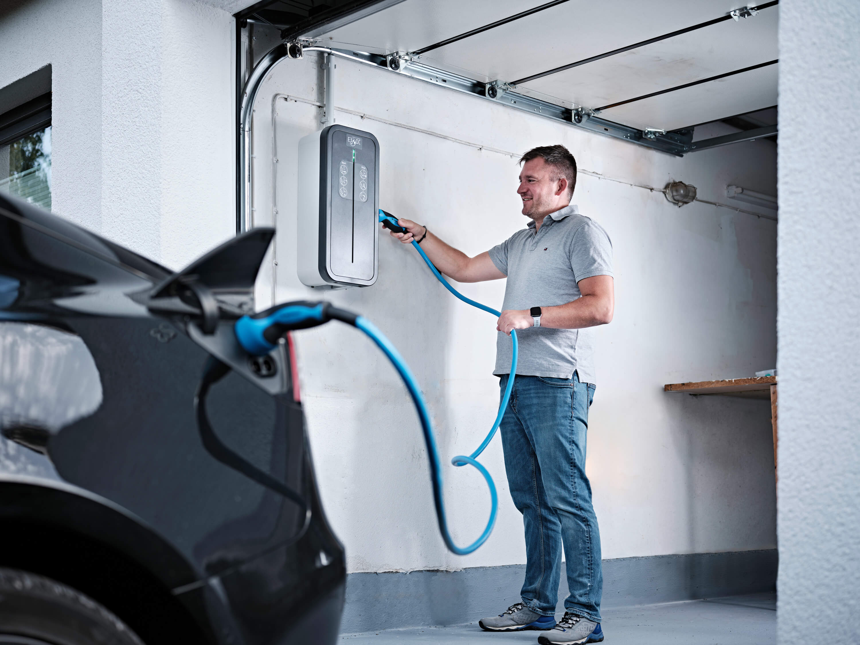 Carsten Paulini lädt ein E-Auto an der Wallbox in der Garage